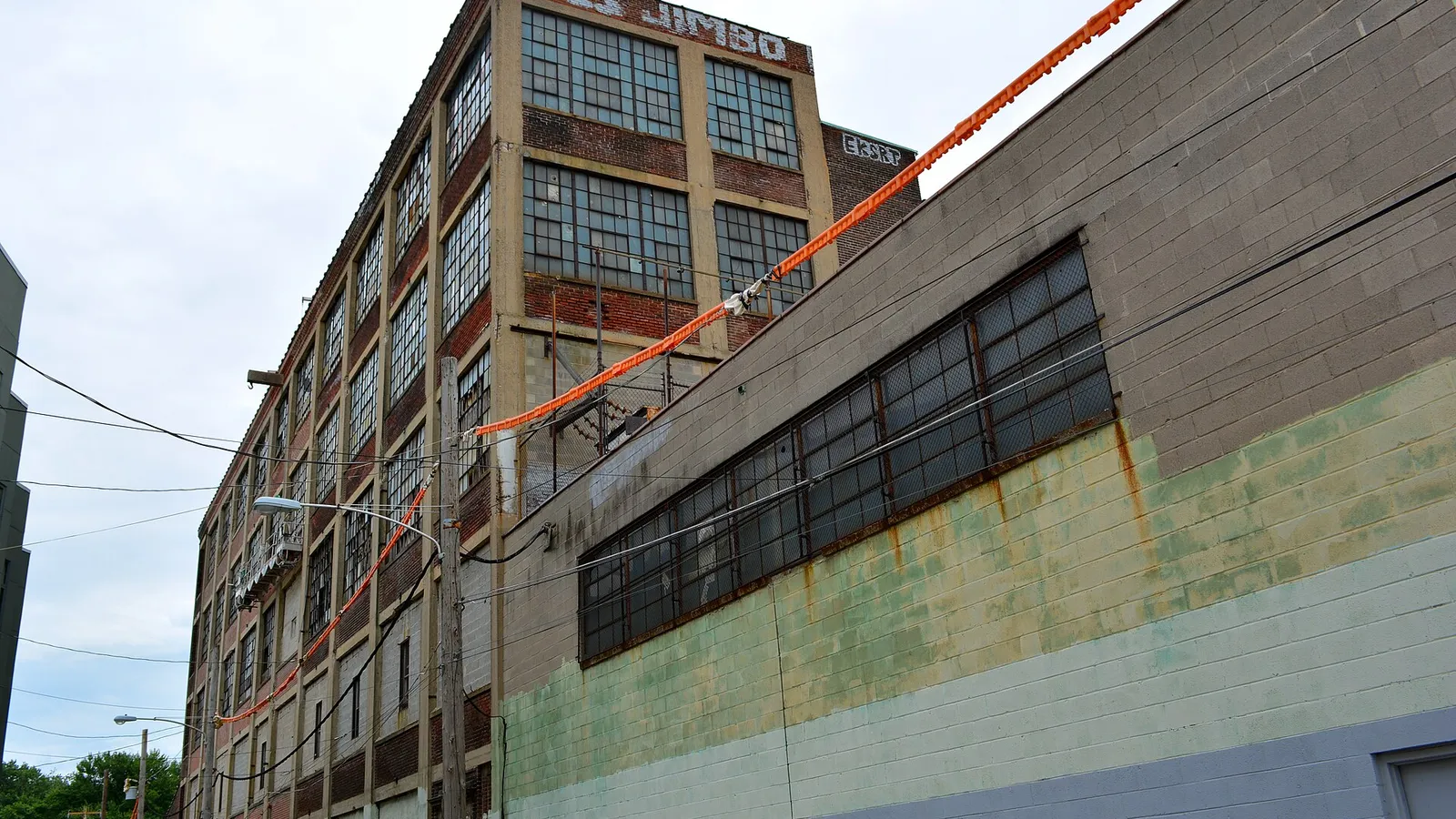 Brick factory exterior with orange industrial hose run