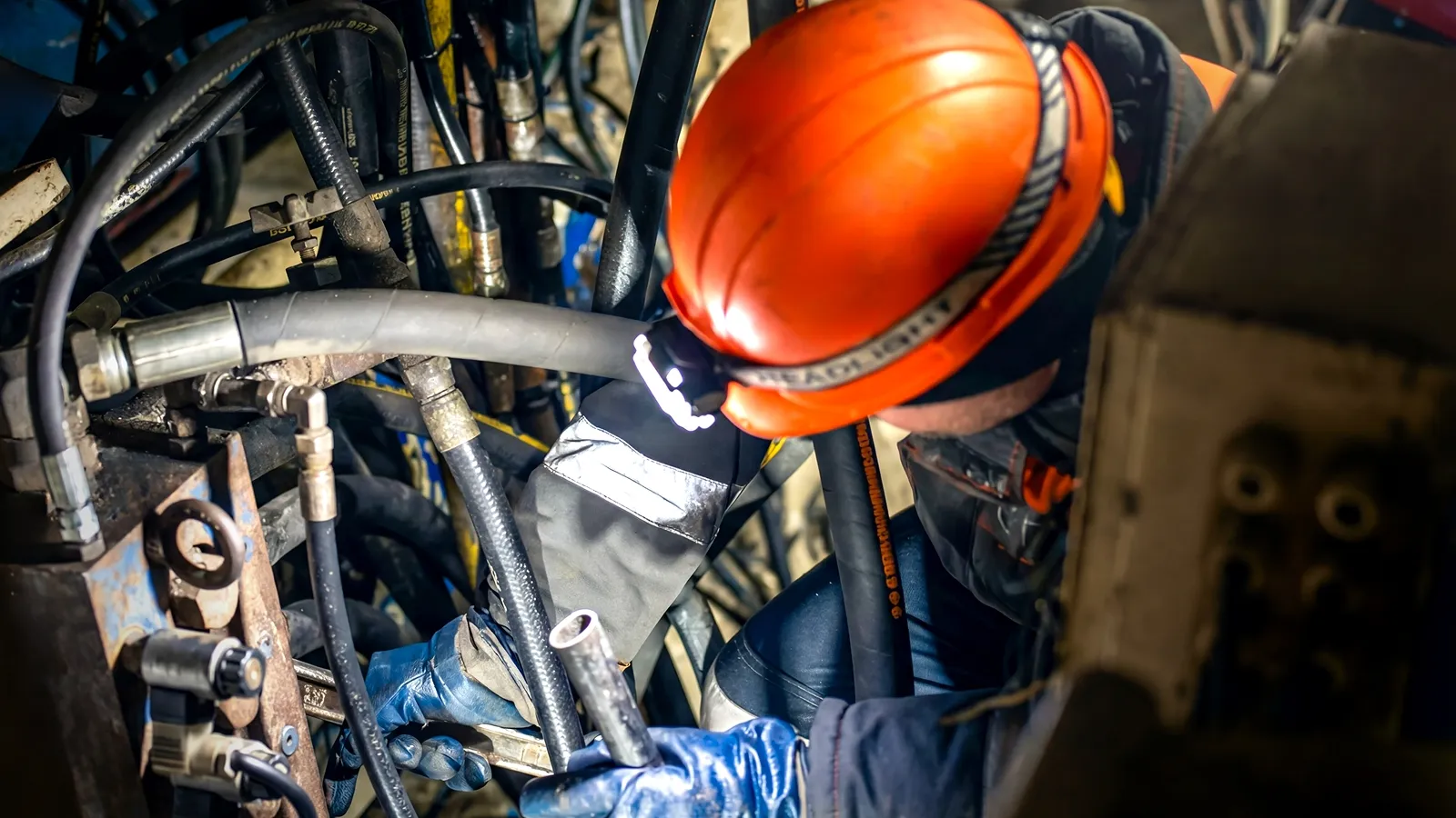 Worker connecting hydraulic hoses on industrial equipment
