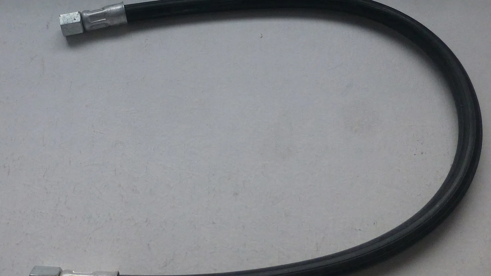 Custom crimped hose assembly with metal fittings on grey background